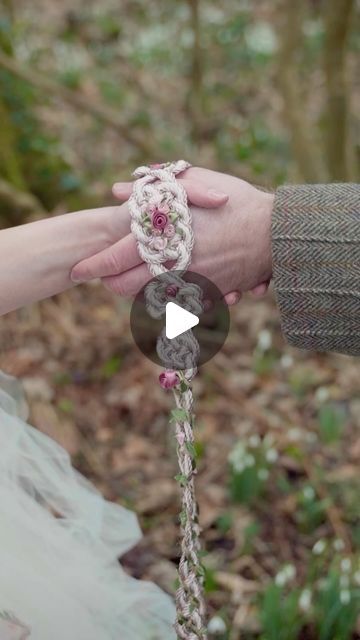 two people holding each other's hand while they are tied to something in the woods