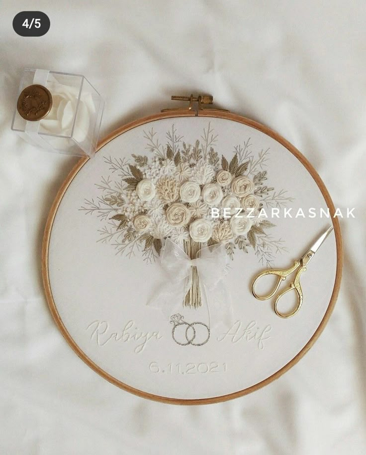 a cross stitch pattern with flowers and two pairs of scissors next to it on a white sheet