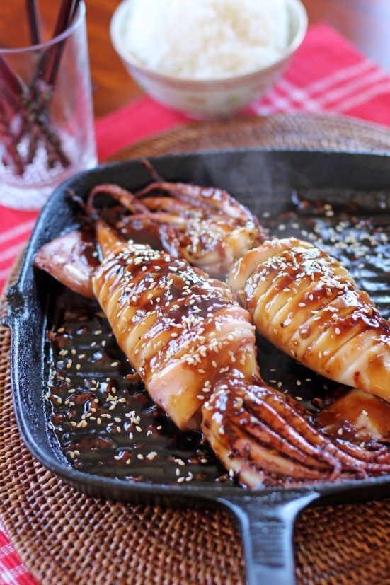 some kind of food that is in a pan on a table with rice and water