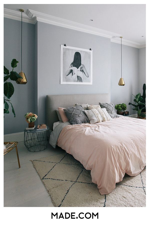 a bedroom with grey walls and light pink bedding in the corner, along with potted plants