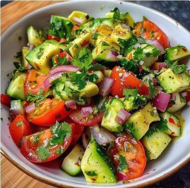 a white bowl filled with cucumber, tomatoes and other vegtables