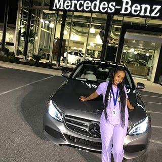 a woman standing in front of a mercedes benz