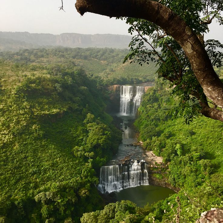 a large waterfall surrounded by lush green trees