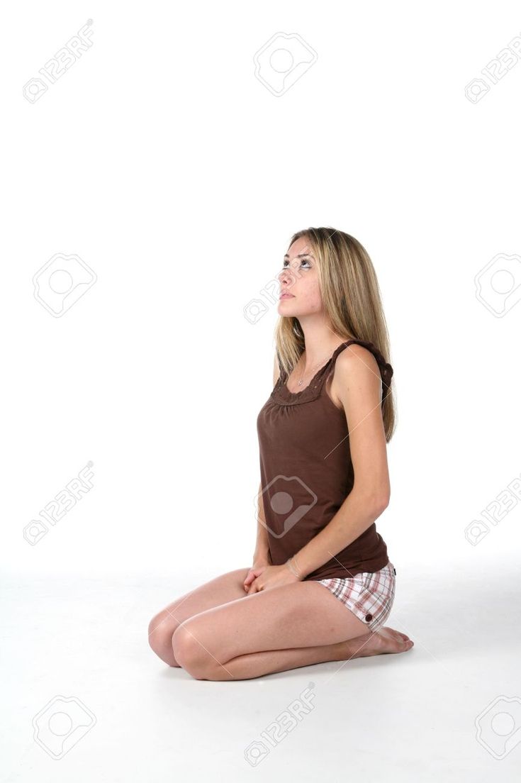 a young woman sitting on the floor with her legs crossed and looking up at something