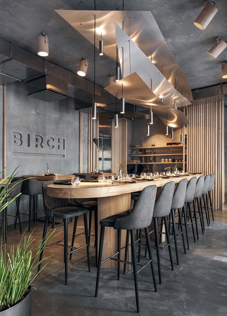 a restaurant with long tables and chairs in the center, surrounded by potted plants