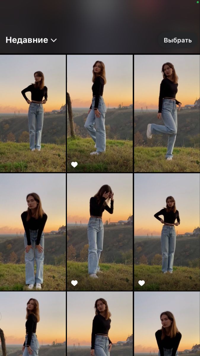 a woman standing on top of a grass covered field next to a tree in front of a sunset