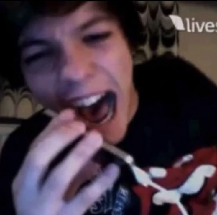 a young man is eating something with his mouth wide open and tongue out, while wearing a black t - shirt