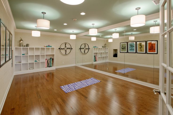 an empty room with hard wood floors and mirrors on the wall, yoga mats on the floor