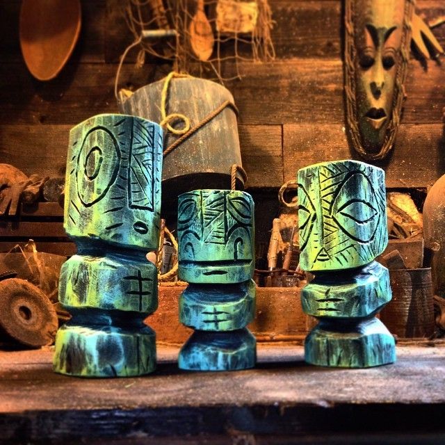 three blue and green vases sitting on top of a wooden table next to other items