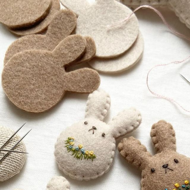 several different types of felt ornaments on a white table with pins and needles in the shape of bunnies