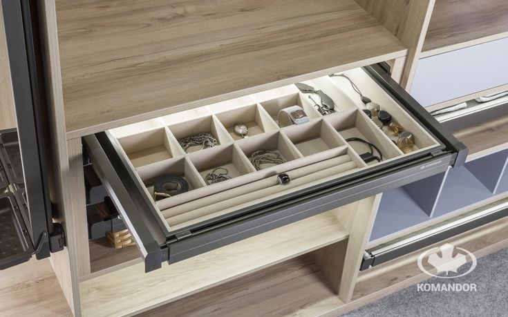 an open drawer with many rings and bracelets in it on the inside of a wooden cabinet