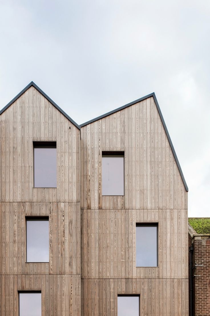 three windows are on the side of a building that is made out of plywood