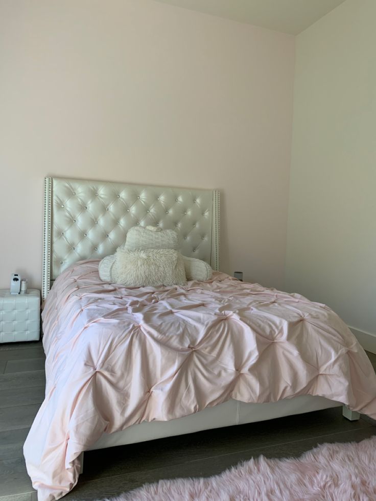 a white bed sitting in a bedroom on top of a hard wood floor next to a wall