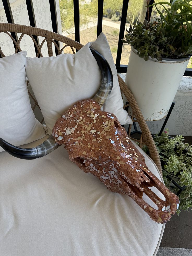 an animal's head is sitting on top of a chair next to a potted plant