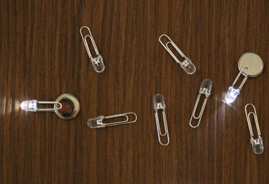 several different types of paper clips on a wooden surface