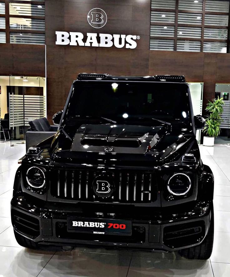 the front end of a black jeep in a showroom with brabus logo on it