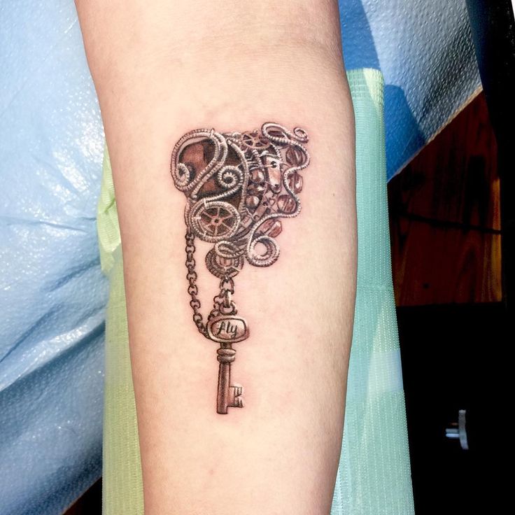 a woman's arm with a tattoo on it and a key attached to the wrist