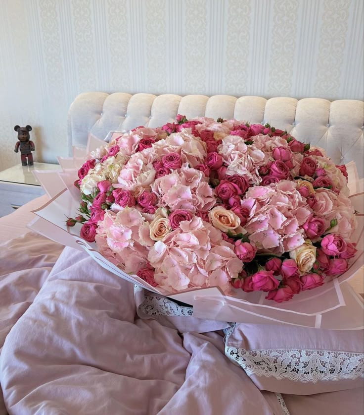 a large bouquet of pink and white flowers on a bed