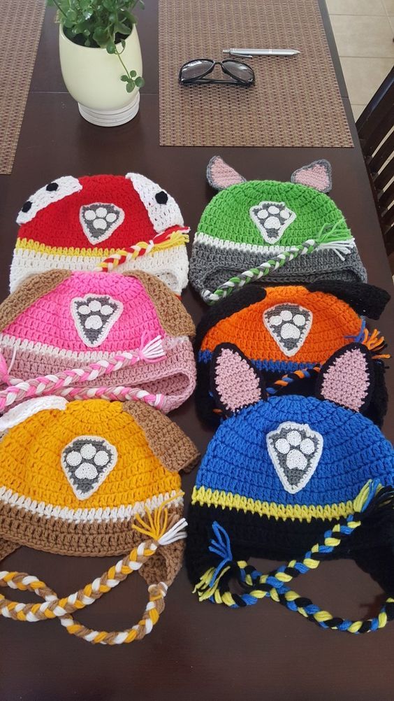 four crocheted hats are sitting on a table