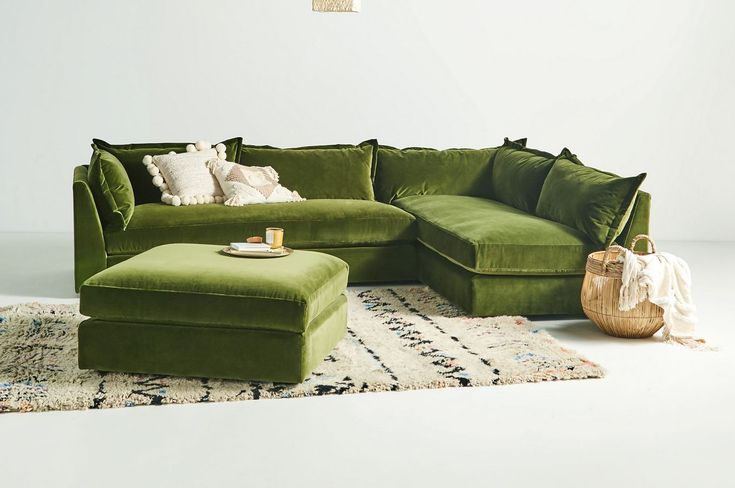 a living room with a large green couch and footstool next to a rug