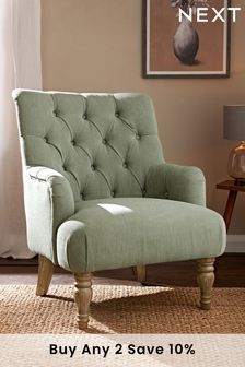 a green chair sitting on top of a rug in front of a wall mounted painting