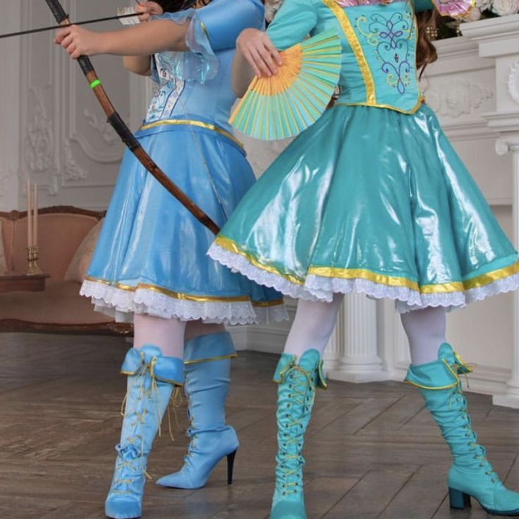 two women dressed in costumes holding umbrellas and bows, standing next to each other