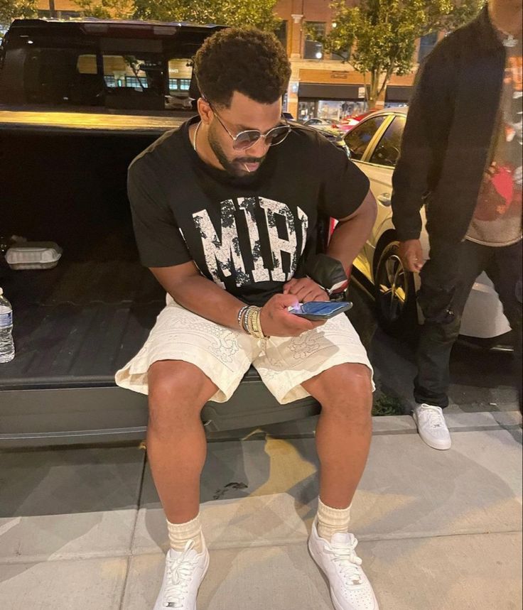 a man sitting on the back of a truck while looking at his cell phone