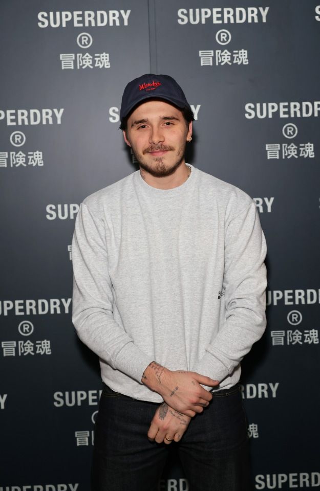 a man standing in front of a wall with the words superdry written on it