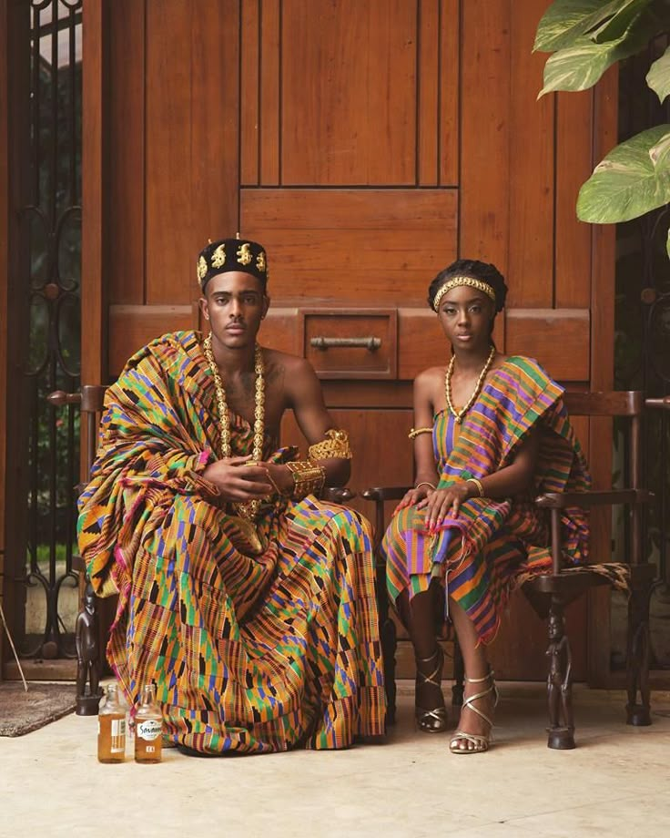 two people sitting next to each other in front of a wooden door wearing colorful clothing