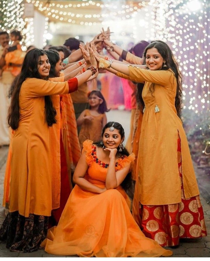 four women in orange dresses are holding their hands up to each other as they pose for the camera