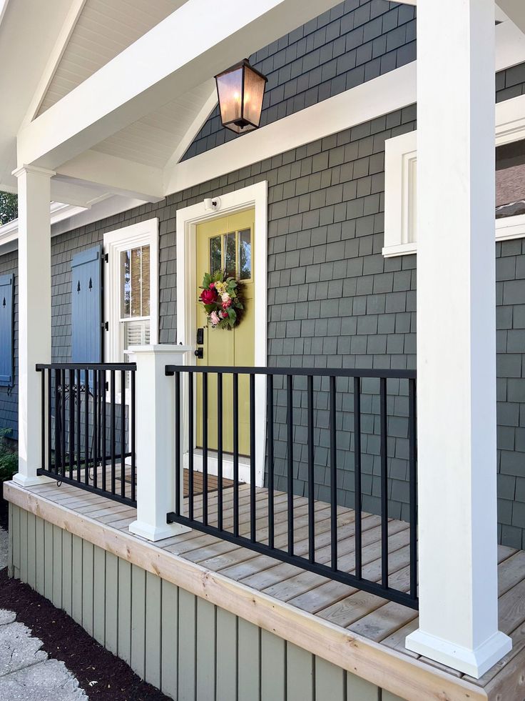 a house with a yellow door and black railing on the front porch is shown in this image