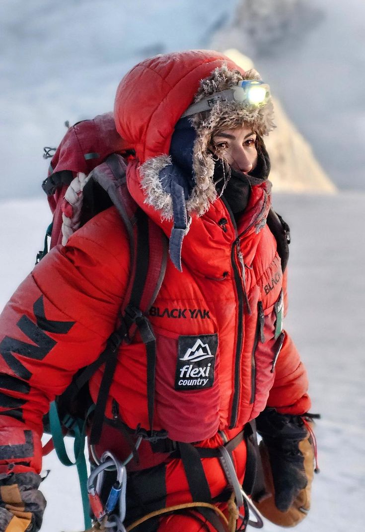 a man in red jacket carrying skis on top of snow covered ground