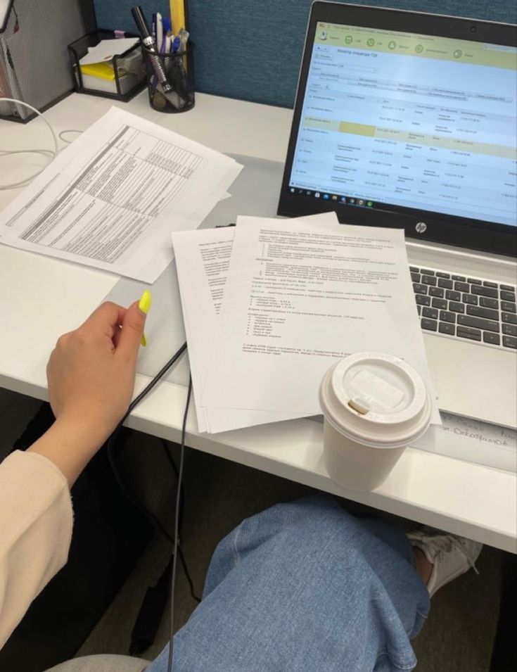 a person is sitting at a desk with papers and a laptop on top of it