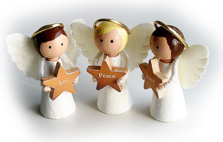 three angel figurines holding wooden stars with the words peace and joy written on them