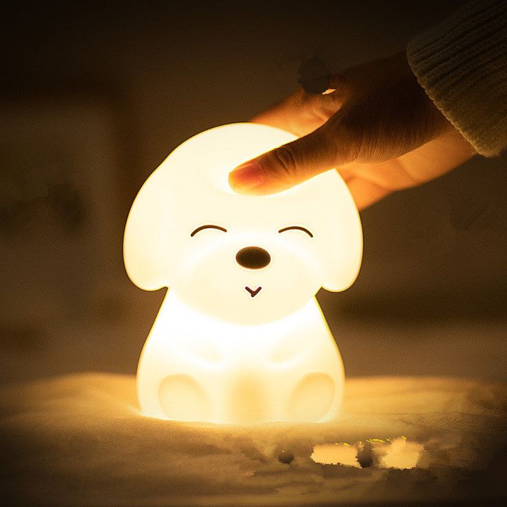 a person touching the light on a small dog shaped lamp with its eyes closed and mouth wide open