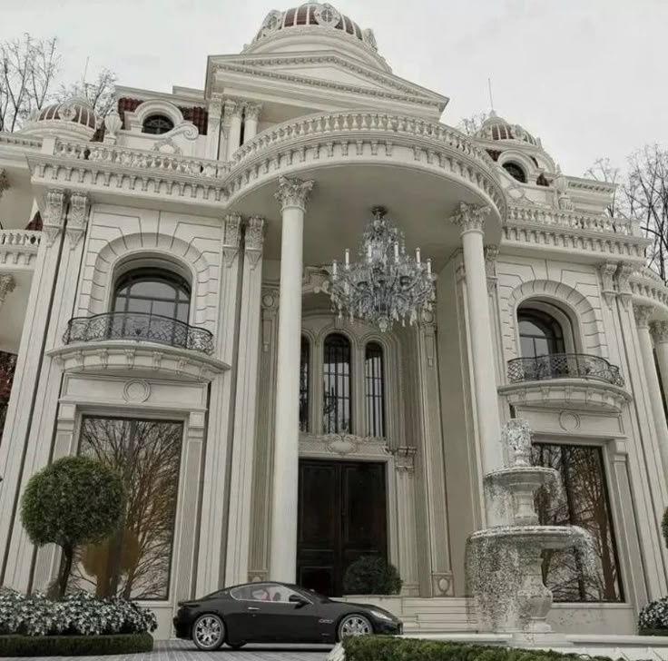 a black car is parked in front of a large white building with columns and chandeliers