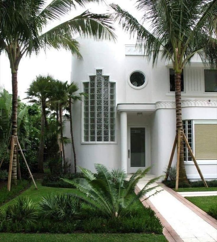 a white house surrounded by palm trees and greenery