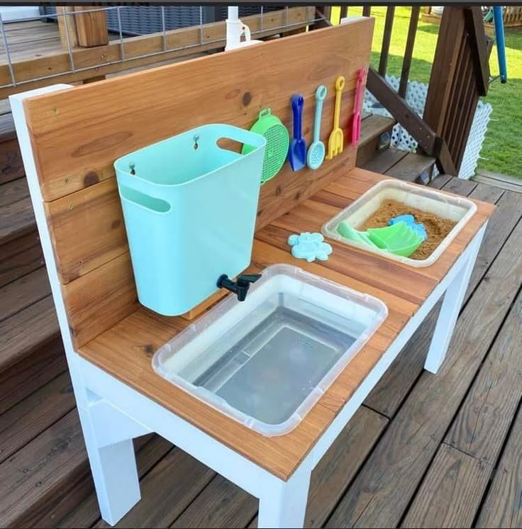 an outdoor play table with ice buckets and cleaning supplies on the back deck area