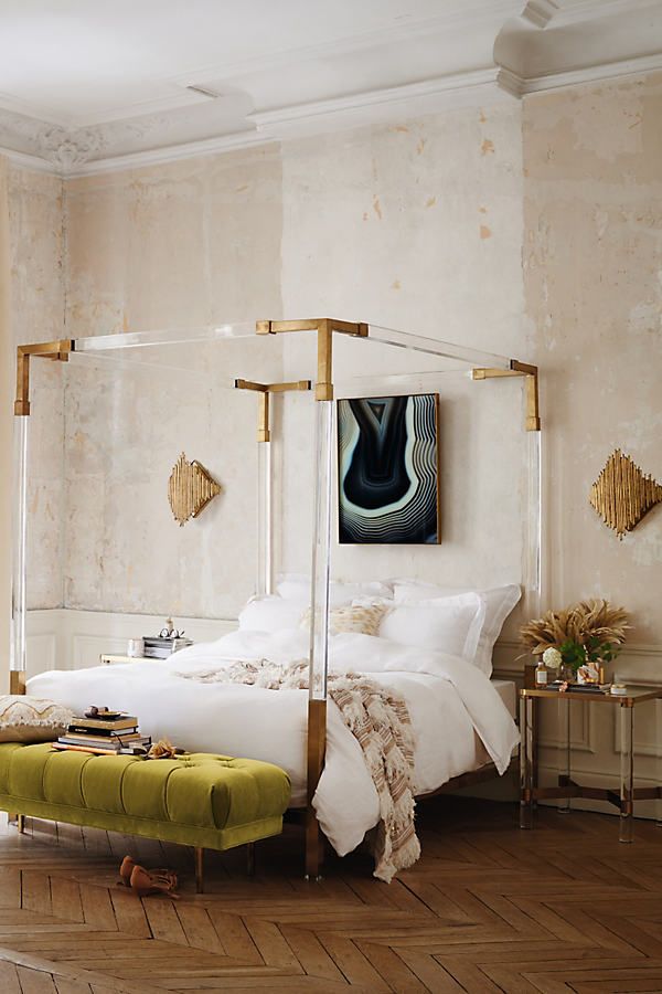 a bedroom with a four poster bed and yellow foot stool