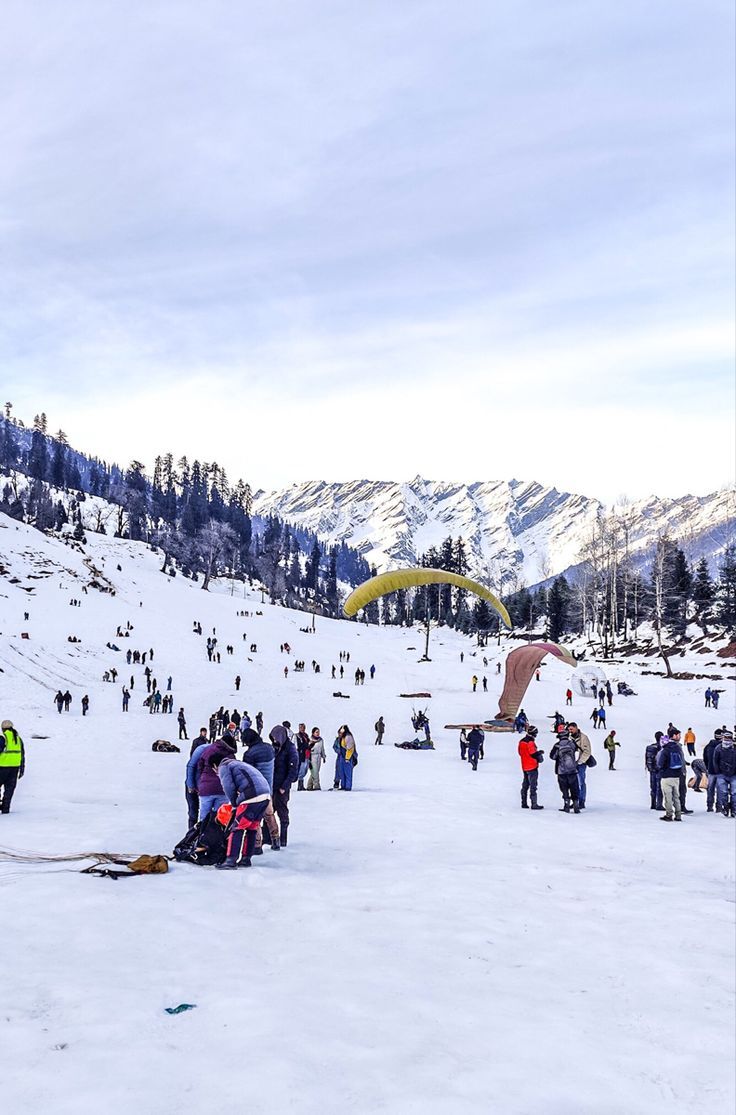 a group of people standing on top of a snow covered slope next to a mountain