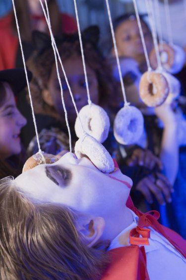 a group of children looking at doughnuts hanging from strings in front of them