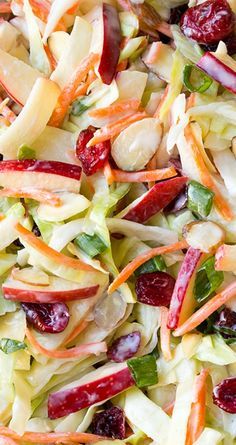 a salad with cranberries, oranges, apples and lettuce in it