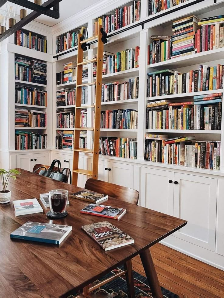 a wooden table sitting in front of a bookshelf filled with lots of books