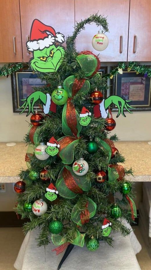 a christmas tree decorated with ornaments in the shape of grino's head and hands