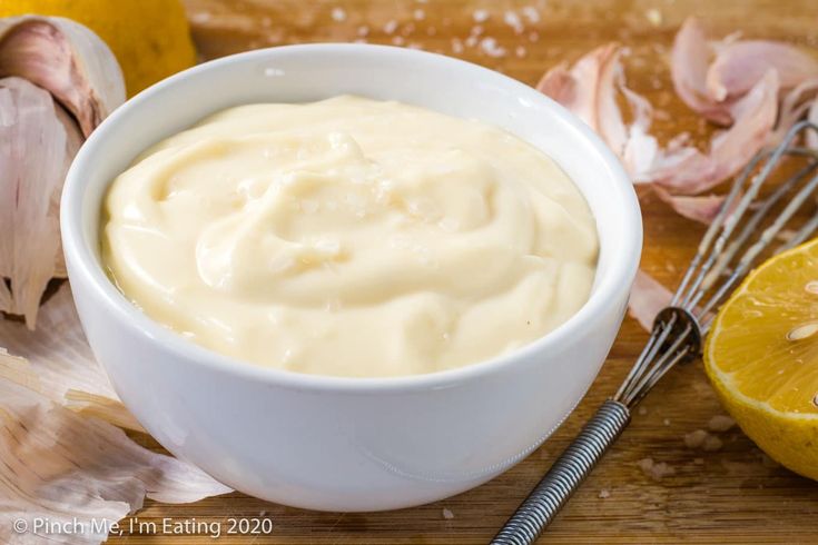 a white bowl filled with mayonnaise next to an orange