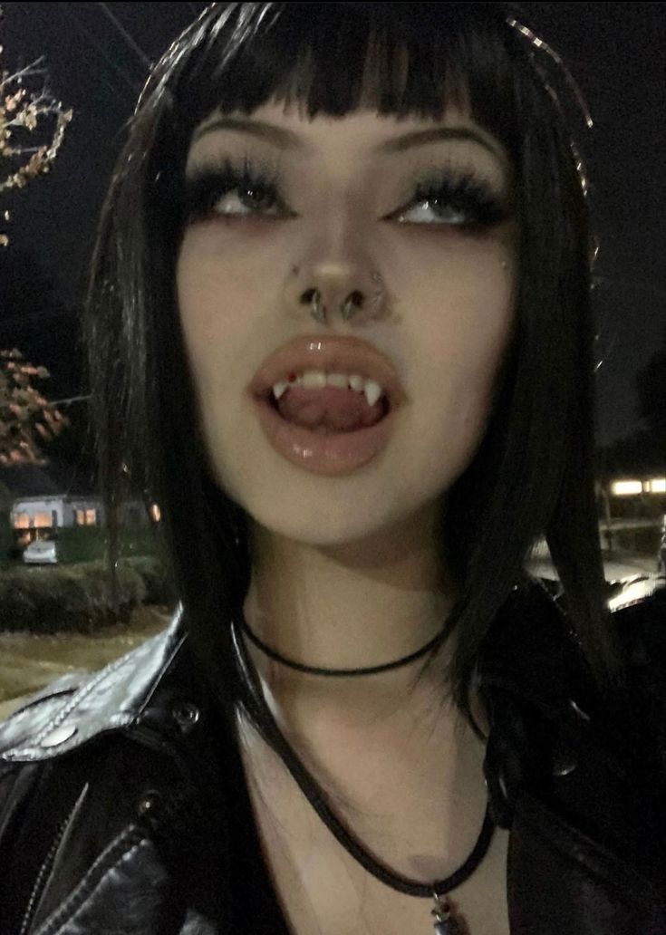 a close up of a person wearing a black leather jacket and piercing on her nose