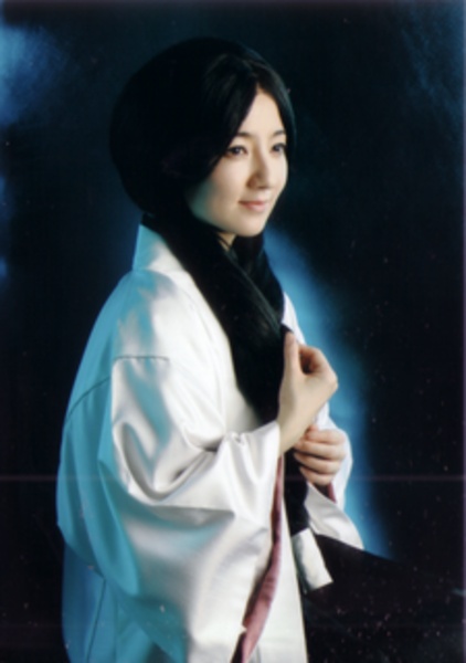 a woman wearing a white kimono posing for a photo with her hands on her hips