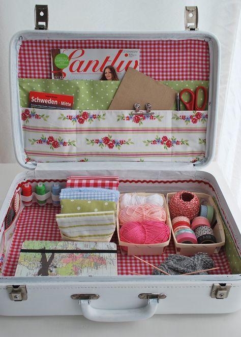 an open suitcase with yarn, scissors and other crafting items in it on a table