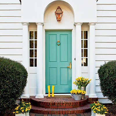 a blue front door with two planters on the steps next to it and yellow flowers