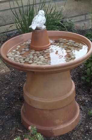 a birdbath with rocks in it and a small white statue sitting on top